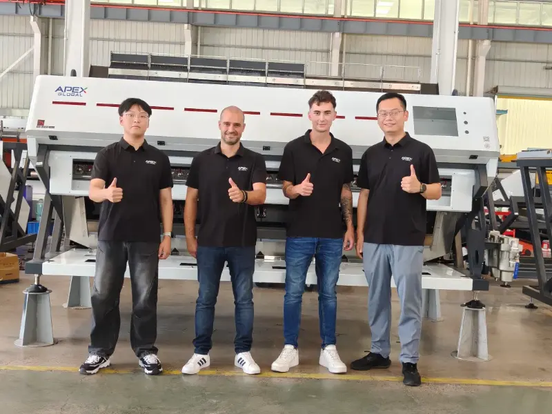 Group photo of APEX team and Spanish authorized distributor after systematic technical training in front of optical sorting machine at factory workshop