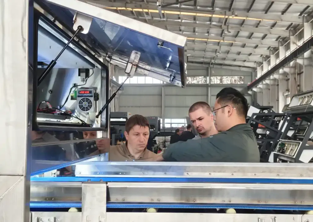 Russian client raises questions about belt‑type optical sorting machine during factory workshop visit