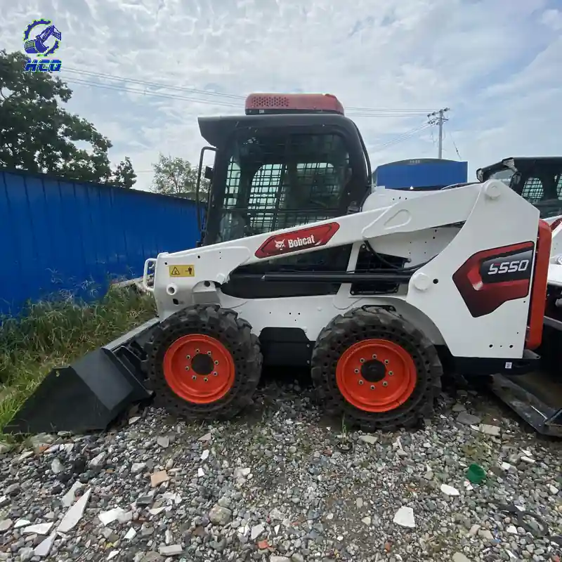 BOBCAT S550滑移装载机整机侧面视图，白色举升臂、橙色轮毂和黑色铲斗清晰可见，HCQ Logo位于左上角