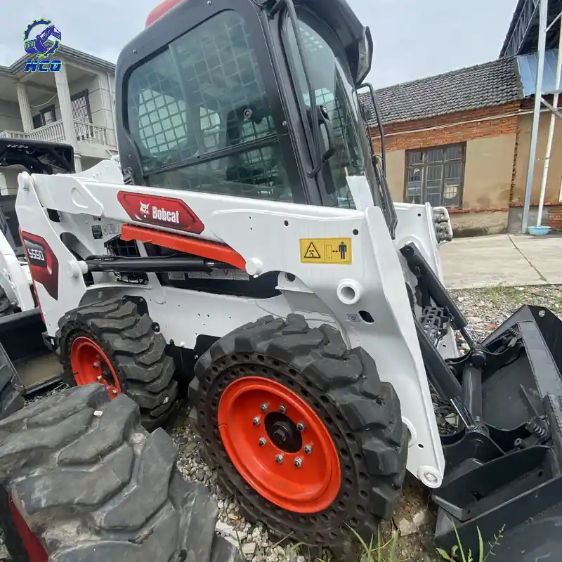BOBCAT S550滑移装载机侧面举升臂、驾驶室和轮胎细节，HCQ Logo位于左上角