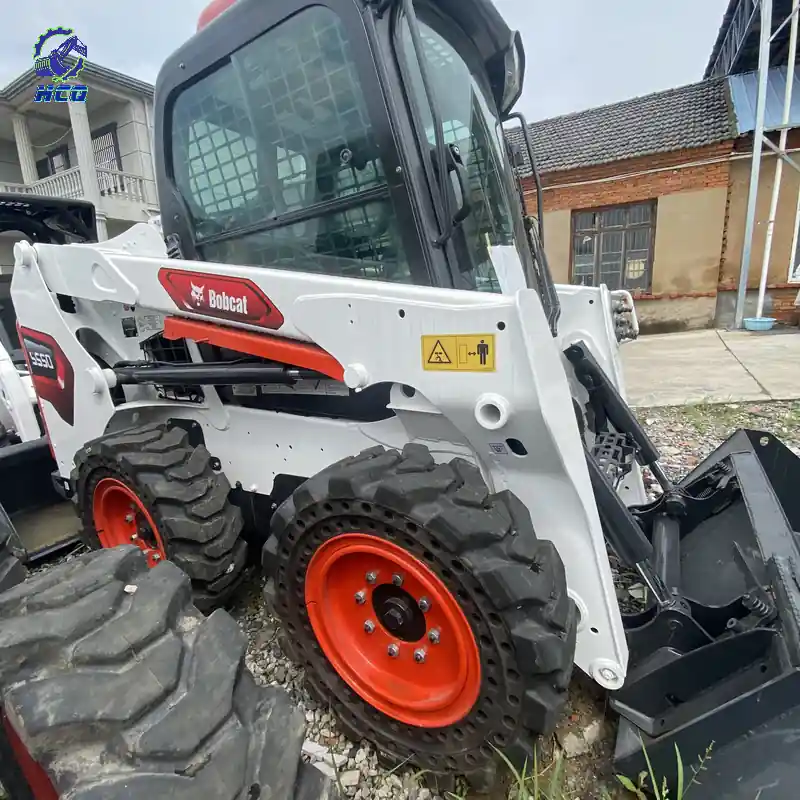 BOBCAT S550滑移装载机举升臂、液压部件、轮胎和铲斗连接处，HCQ Logo位于左上角