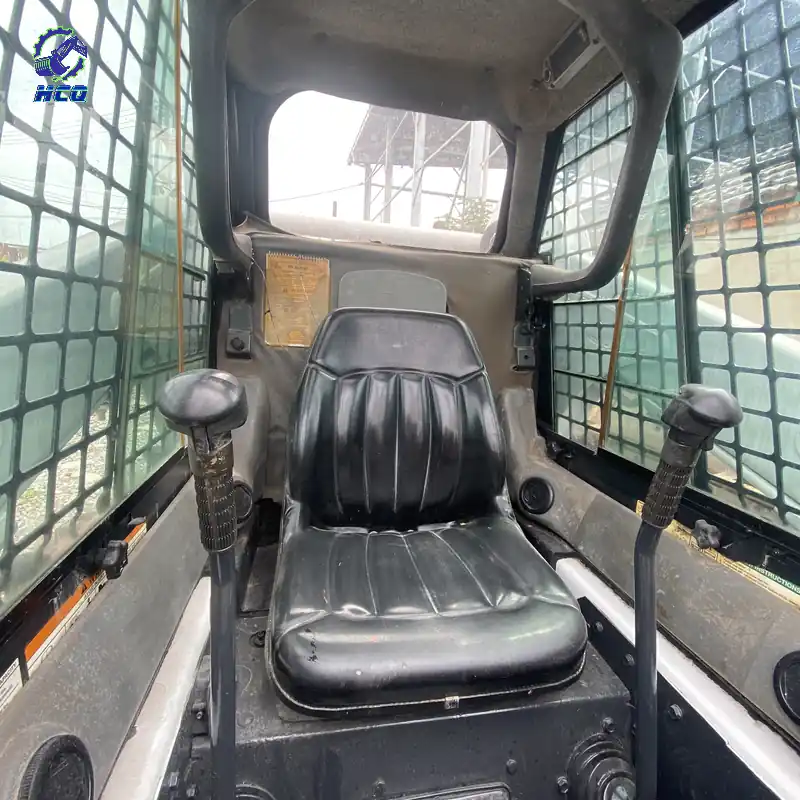 BOBCAT S550滑移装载机驾驶室、座椅、操纵杆和防护网细节，HCQ Logo位于左上角