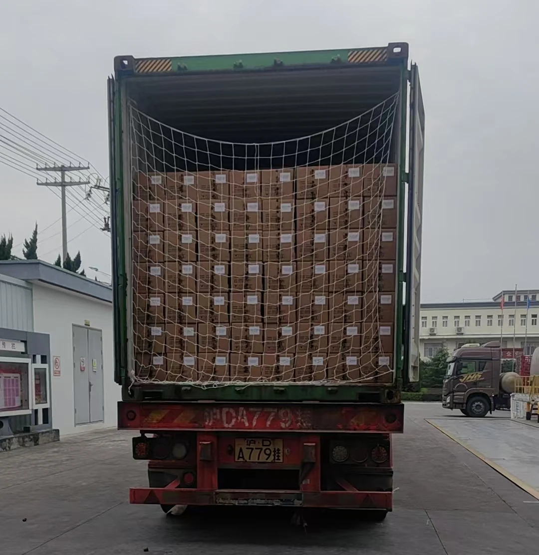 Cajas de botellas de 1 litro cargadas hasta el techo del contenedor, vistas de frente desde las puertas del contenedor.